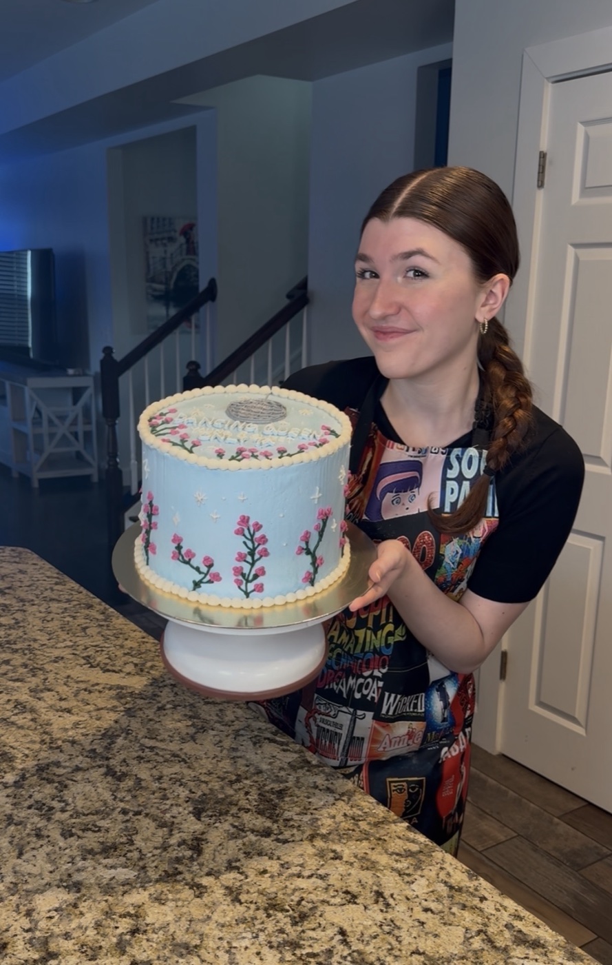 Violet holding a hand-piped buttercream cake in her kitchen