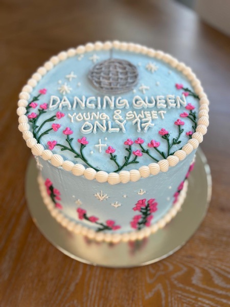 Dusty blue cake with piped silver disco ball, pink wildflowers, and "Dancing Queen" lyric