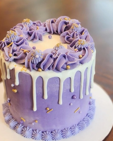 Lavender buttercream cake with ivory drip, rosette crown, gold pearls, and confetti
