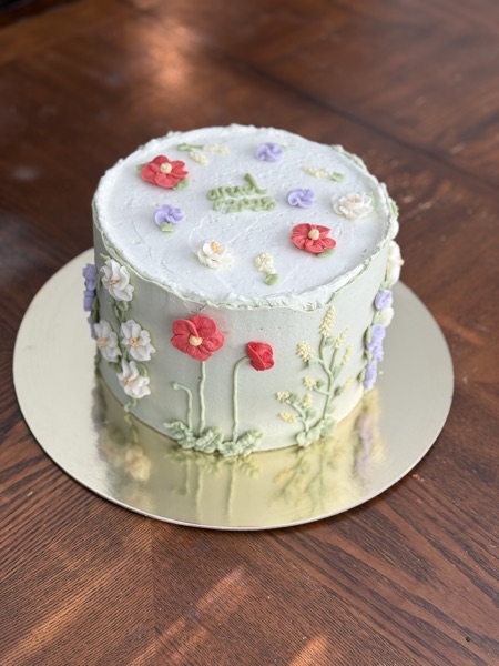 Top-down view of the sage green wildflower cake with red poppies, lavender, and white blossoms
