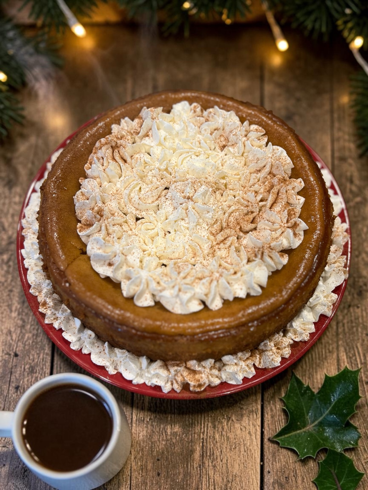 Pumpkin cheesecake topped with whipped cream rosettes dusted with cinnamon, on a red plate