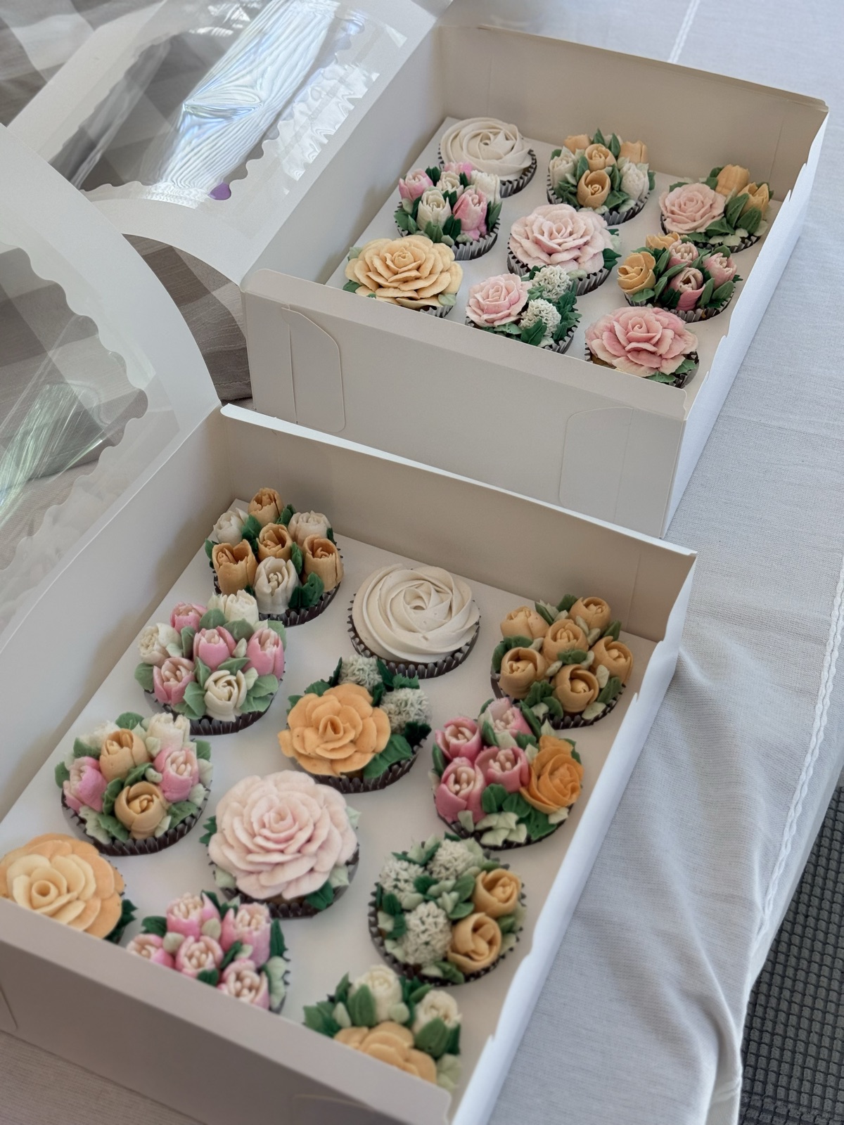 Two boxes of cupcakes side by side with mixed floral designs