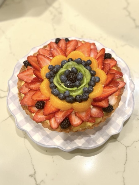 Fruit tart styled as a flower with mandarin segments, kiwi, and strawberries