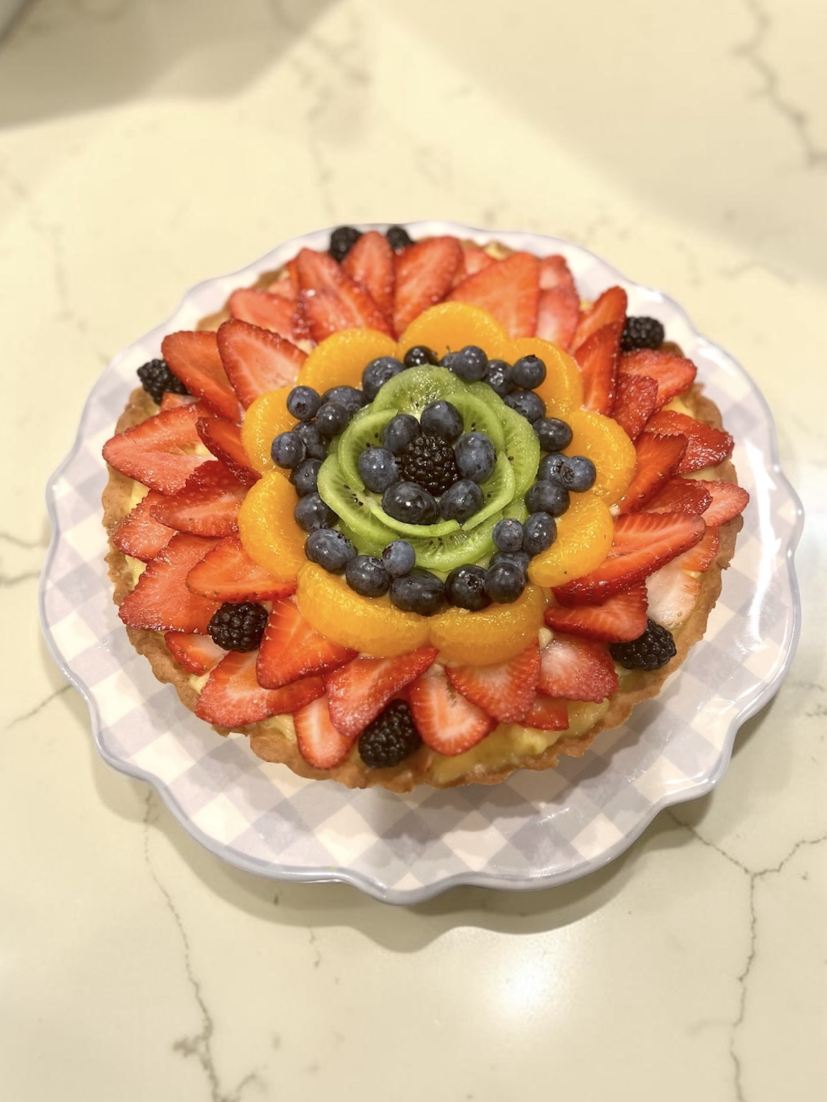 Fruit tart styled as a flower with mandarin segments, kiwi, and strawberries