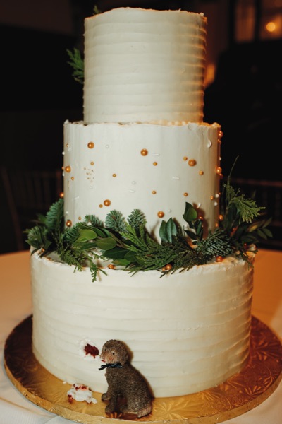 Three-tier textured ivory wedding cake with fresh evergreen and gold pearls