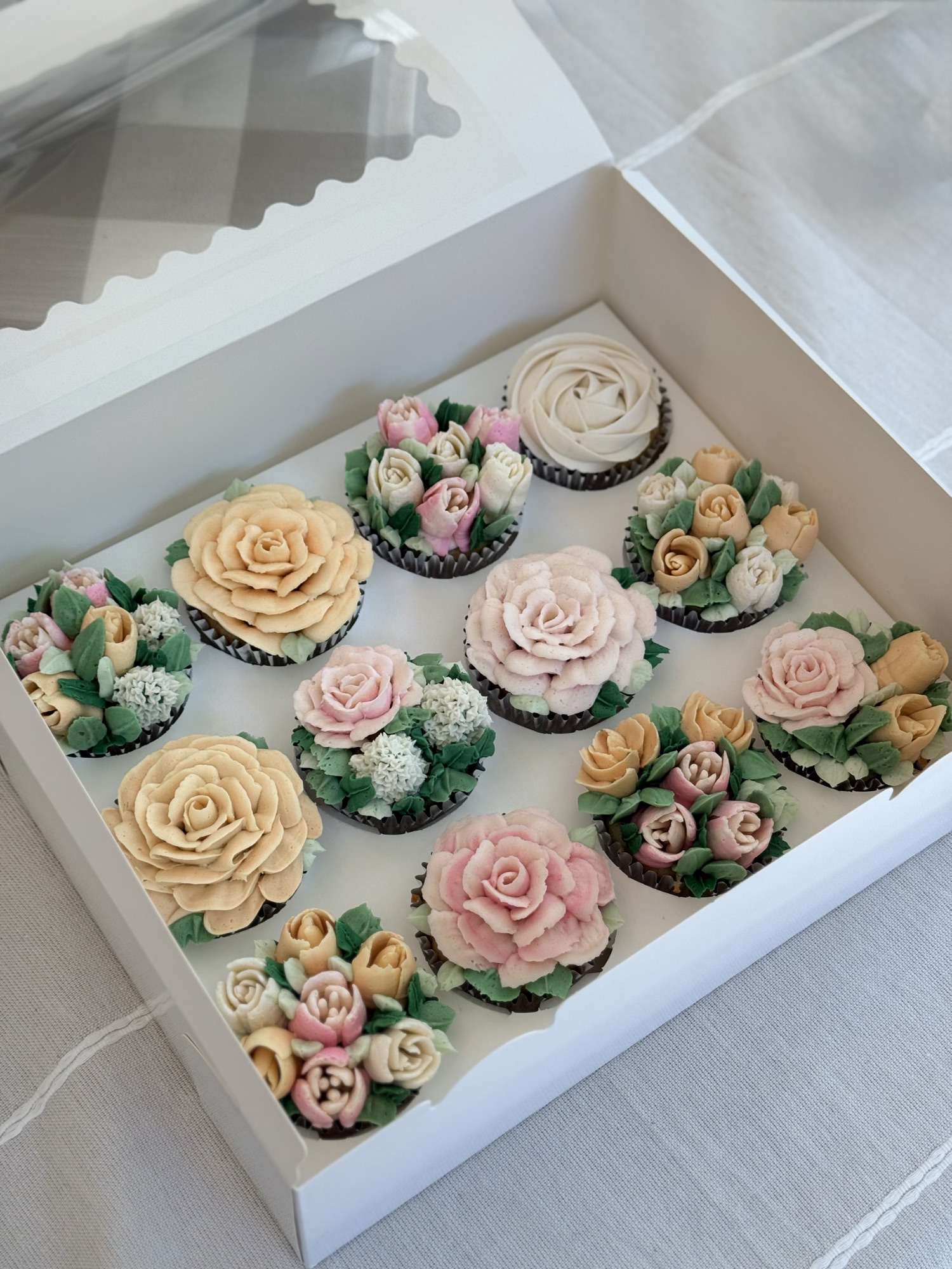 Box of buttercream flower cupcakes in roses, tulips, and hydrangeas