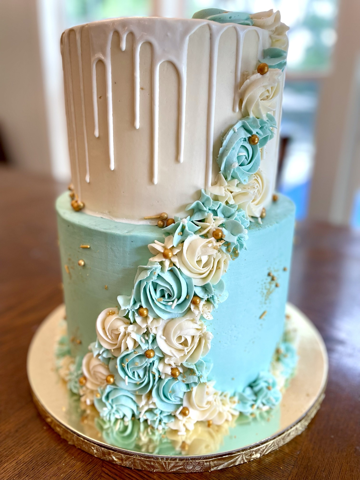 Two-tier teal and ivory cake with cascading buttercream roses